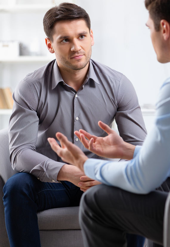 Психотерапевт и пациент сидят и общаются