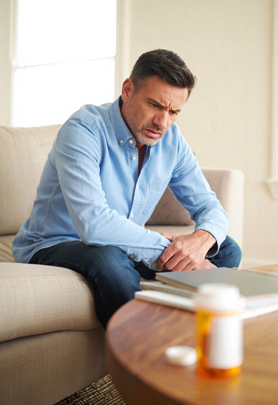 Мужчина с озадаченным лицом сидит на диване